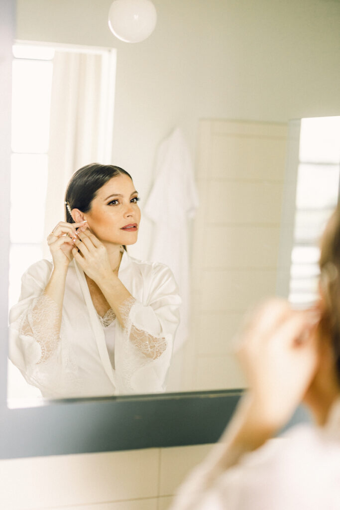 A bride looks in the mirror as she is getting ready for her wedding.