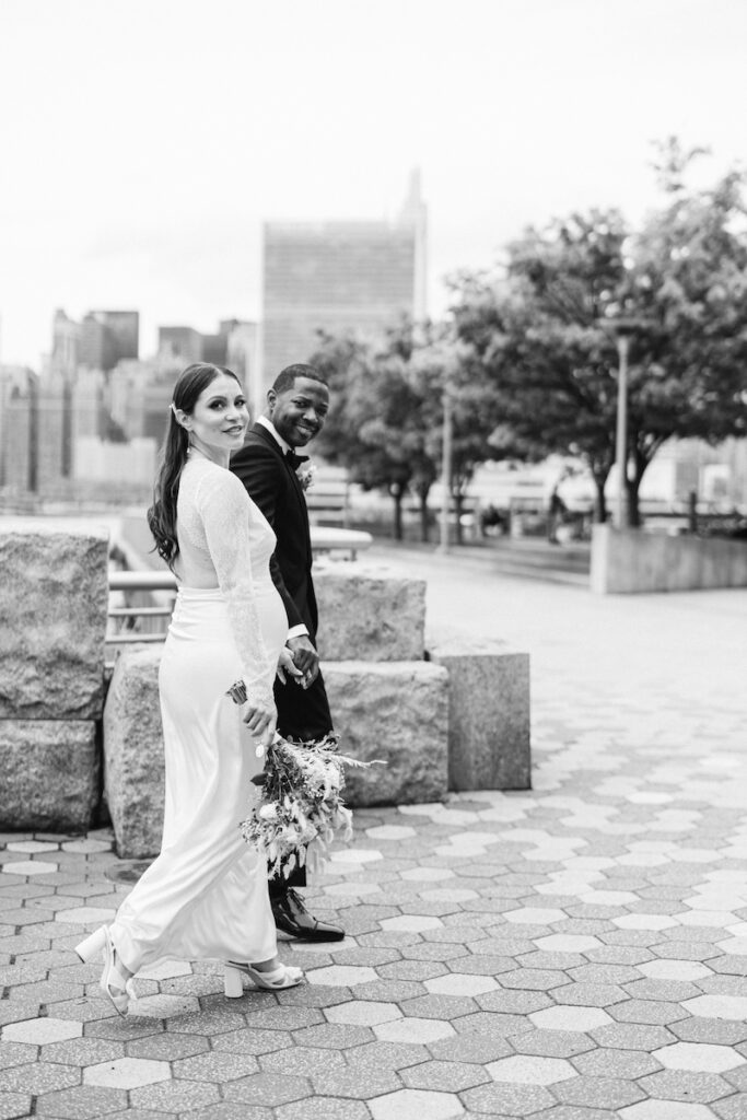 The bride and groom hold hands and walk to the wedding ceremony, crossing the street in New York City, taken by Molli Photo, New York City wedding photographer.