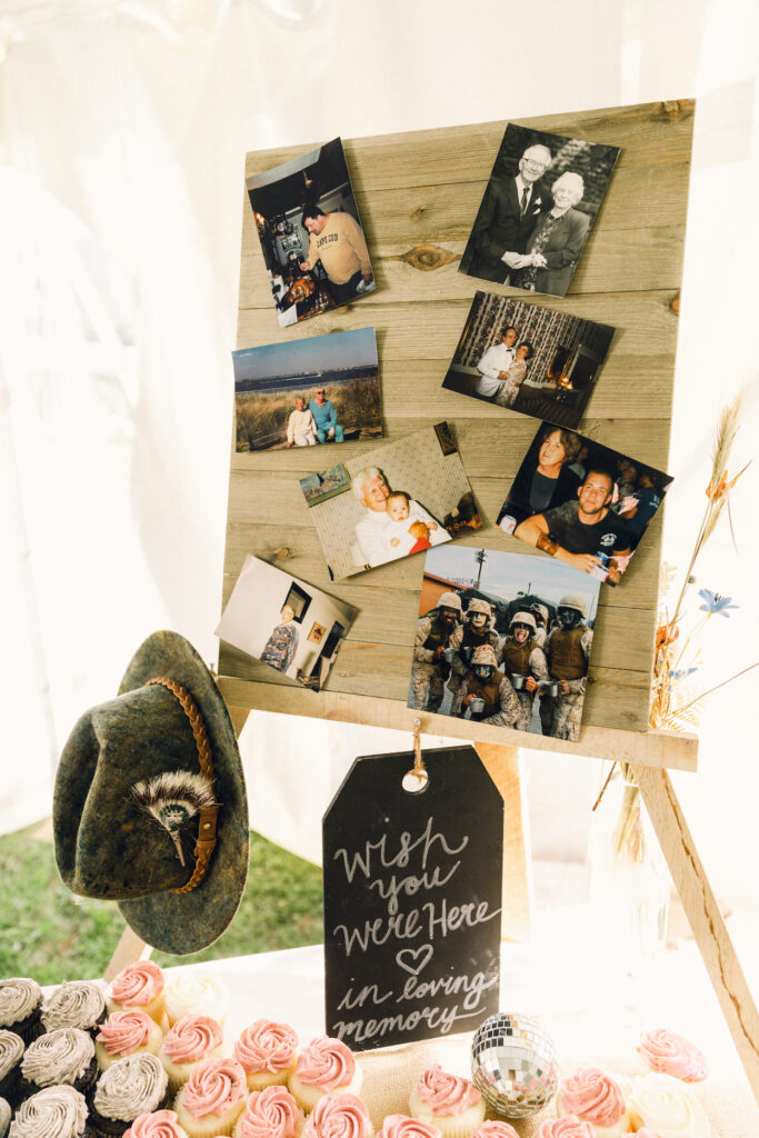 A sign that reads, "wish you were here," with photos of loved ones and keepsakes at a wedding reception.
