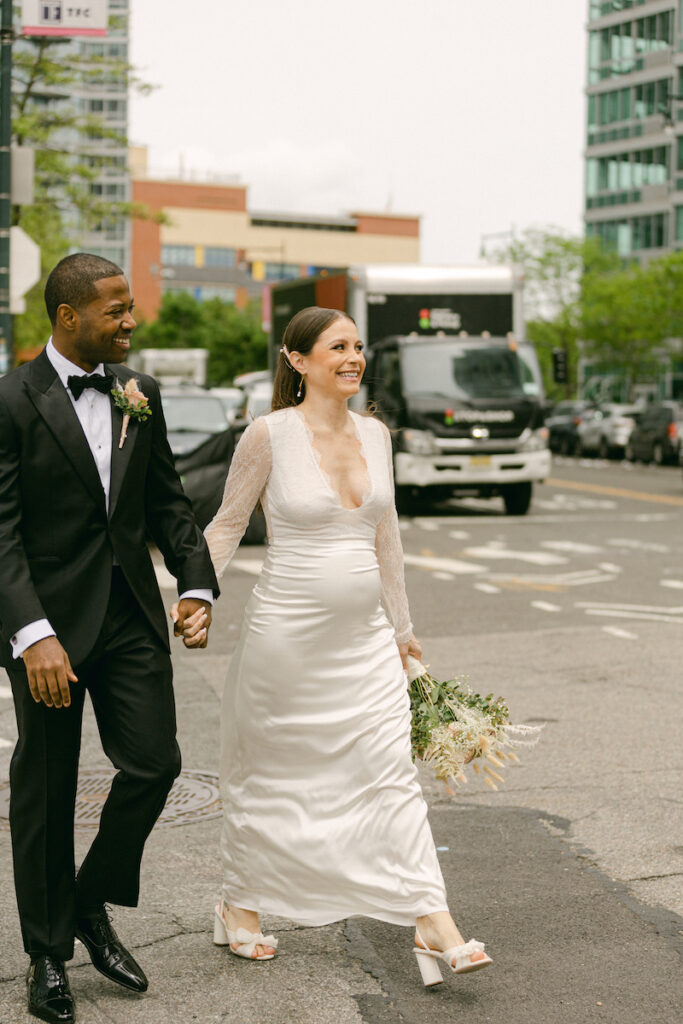 The bride and groom smiles as they walk to the wedding ceremony, crossing the street in New York City, taken by Molli Photo, New York City wedding photographer.