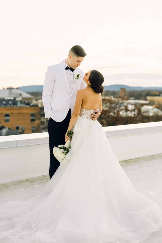 Bride and groom on the rooftop of a hotel with a city view in the backdrop.
