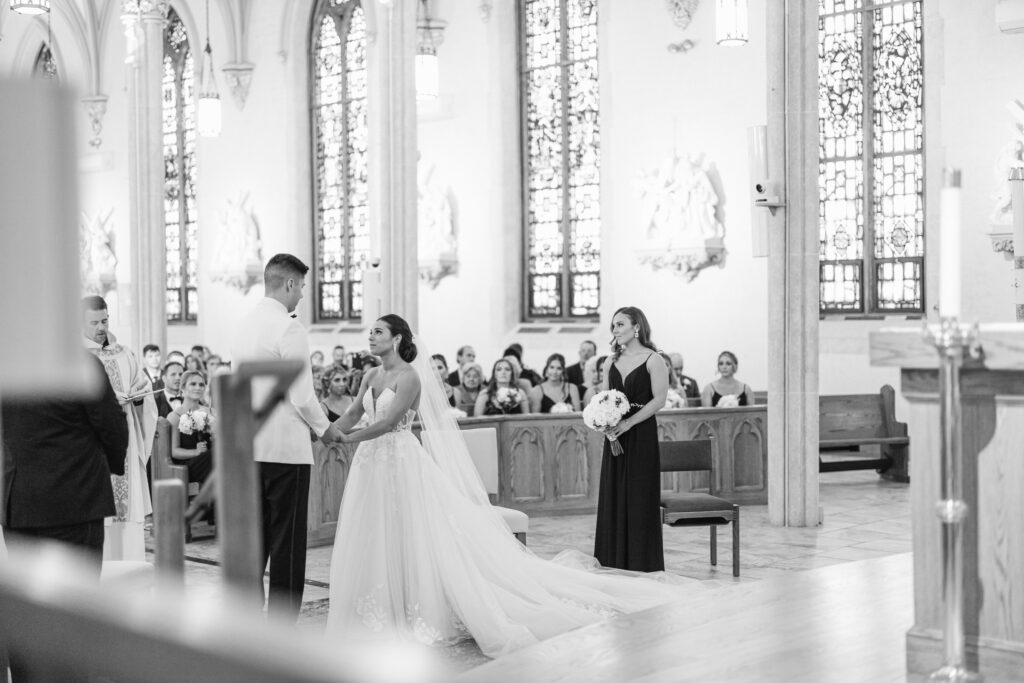 The bride and groom hold hands at the altar at a traditional catholic ceremony at St. Mary's Catholic Church in Upstate New York.