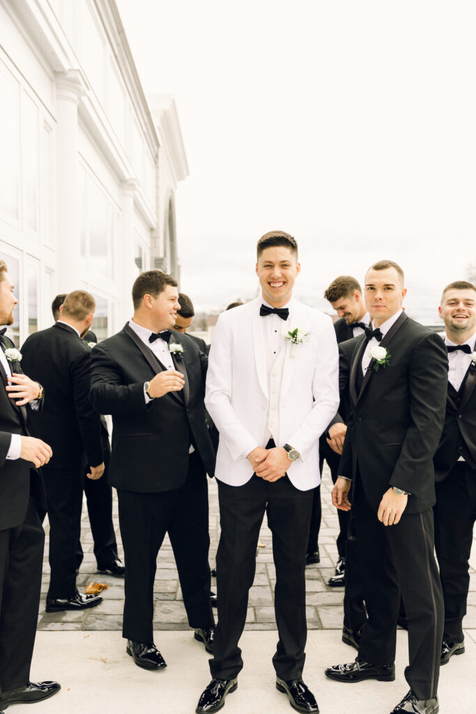 The groom photographed for a wedding with his groomsmen laughing and joking behind him.