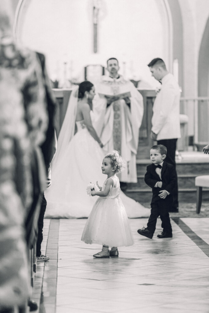 The flower girl walking down the aisle at a catholic ceremony at St. Mary's Catholic Church in New York.