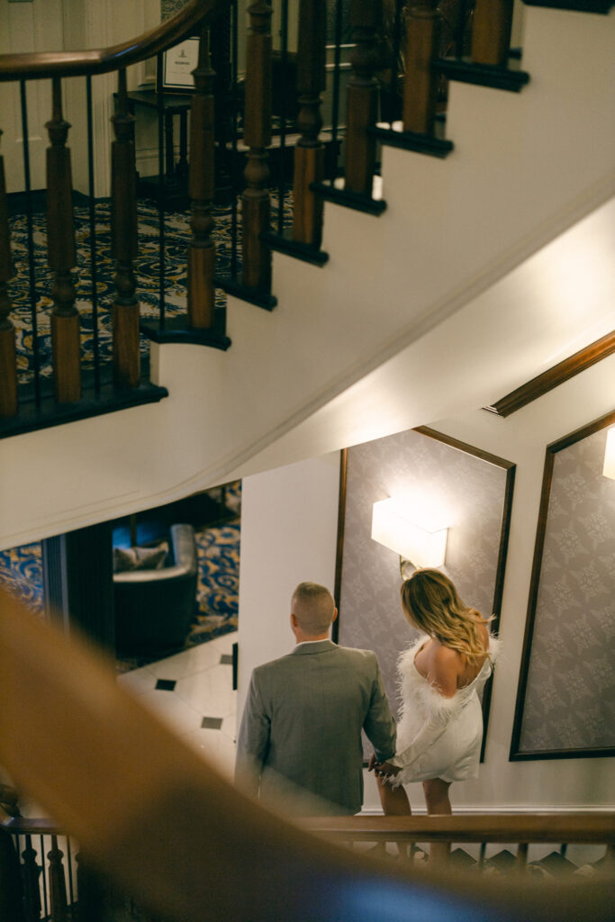Couple walking down staircase at the Adelphi Hotel in New York for their engagement photos.
