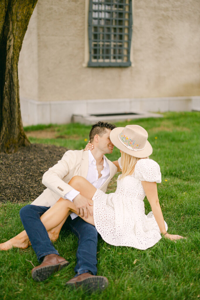 A couple sitting in the grass for an outdoor New York engagement photo session.
