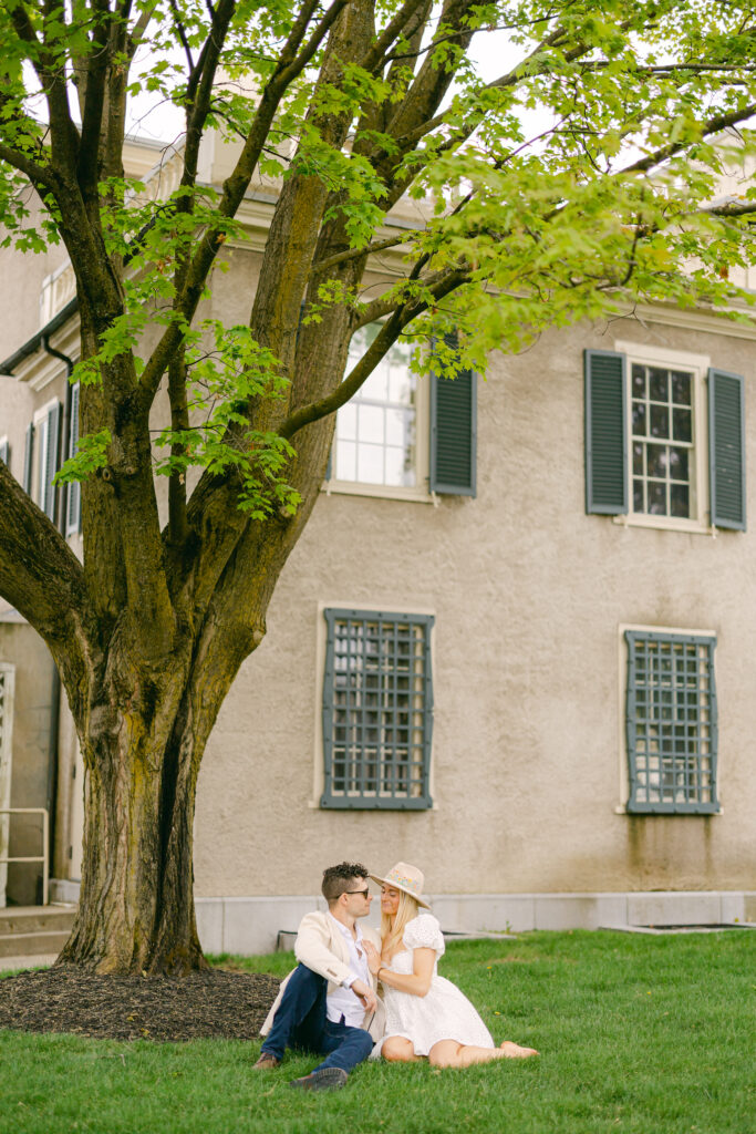 A couple sitting under a tree for an outdoor New York engagement session.