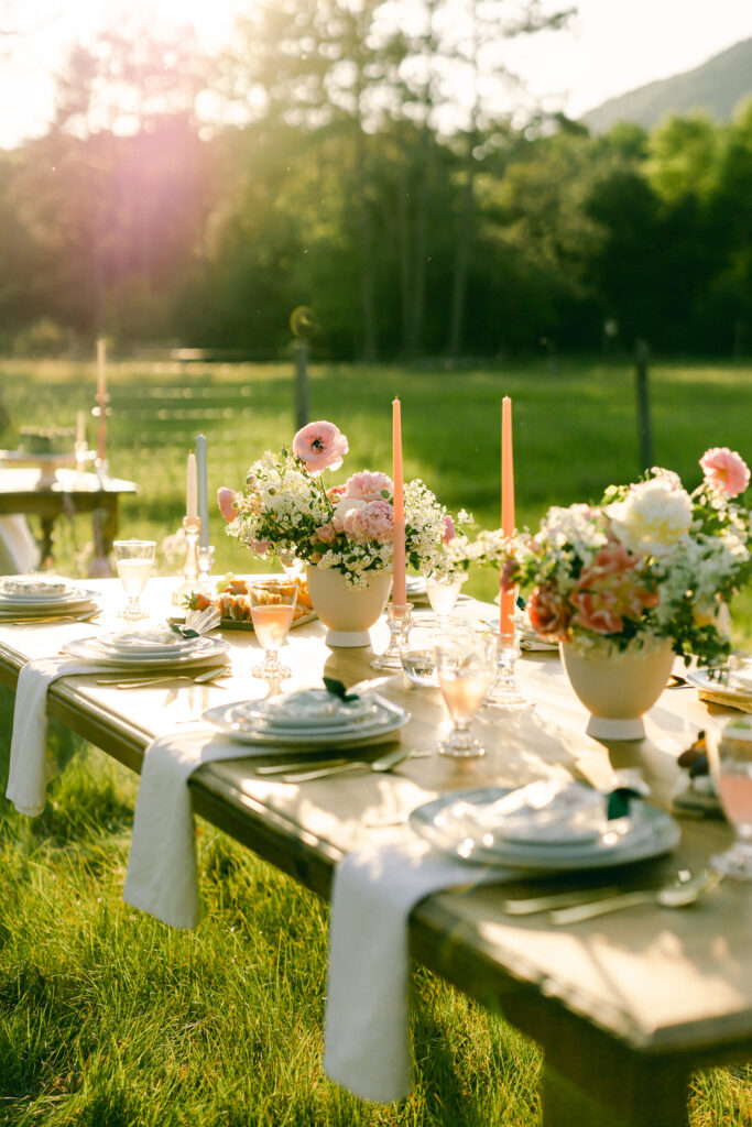 Tablescape of vintage taper candles, pink and blue pastels, white flatware, and pink garden blooms for a garden party wedding.