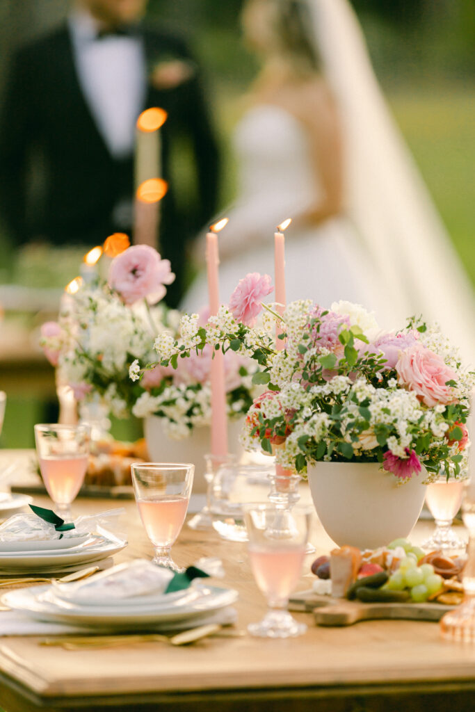 Tablescape of vintage taper candles, pink and blue pastels, white flatware, and pink garden blooms for a garden party wedding.