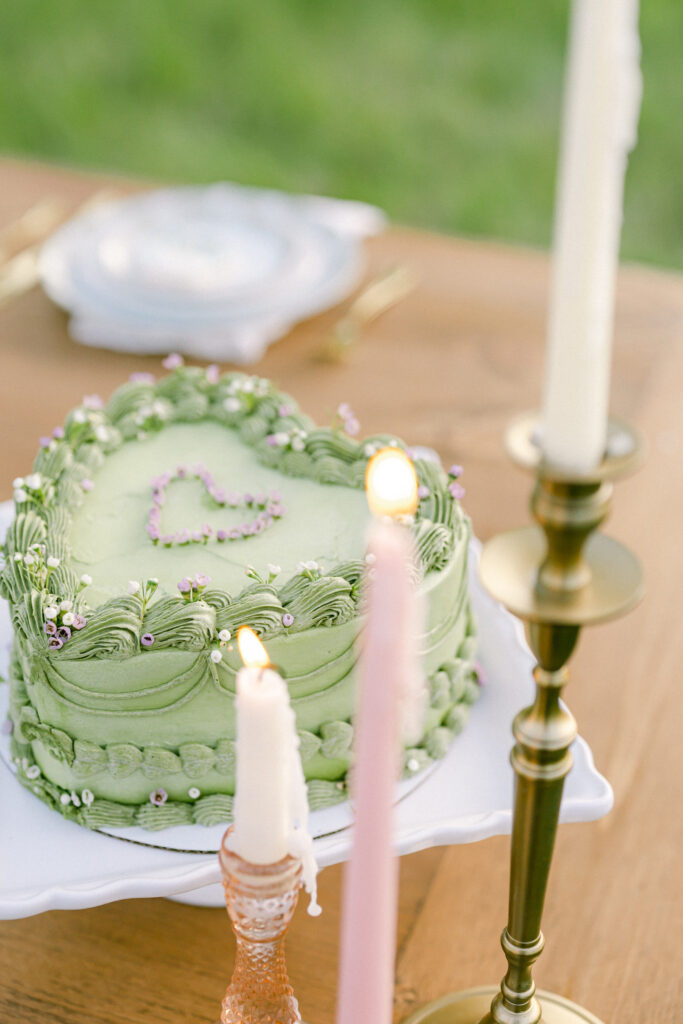 Garden party wedding cake with green icing, a heart shape, and pink and white details.