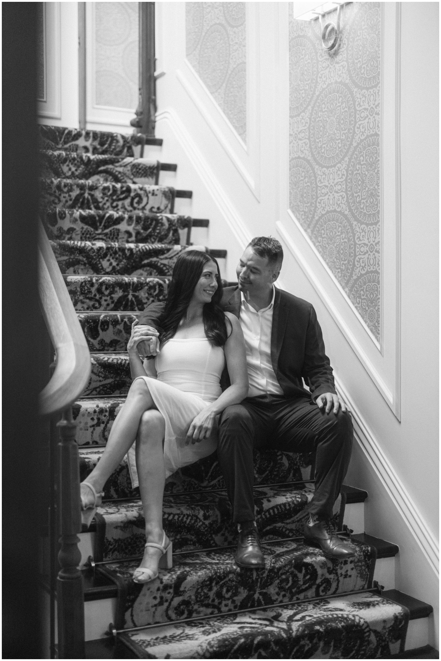 Newlyweds smile at each other while leaning on each other and sitting in the stairs at their the adelphi hotel wedding