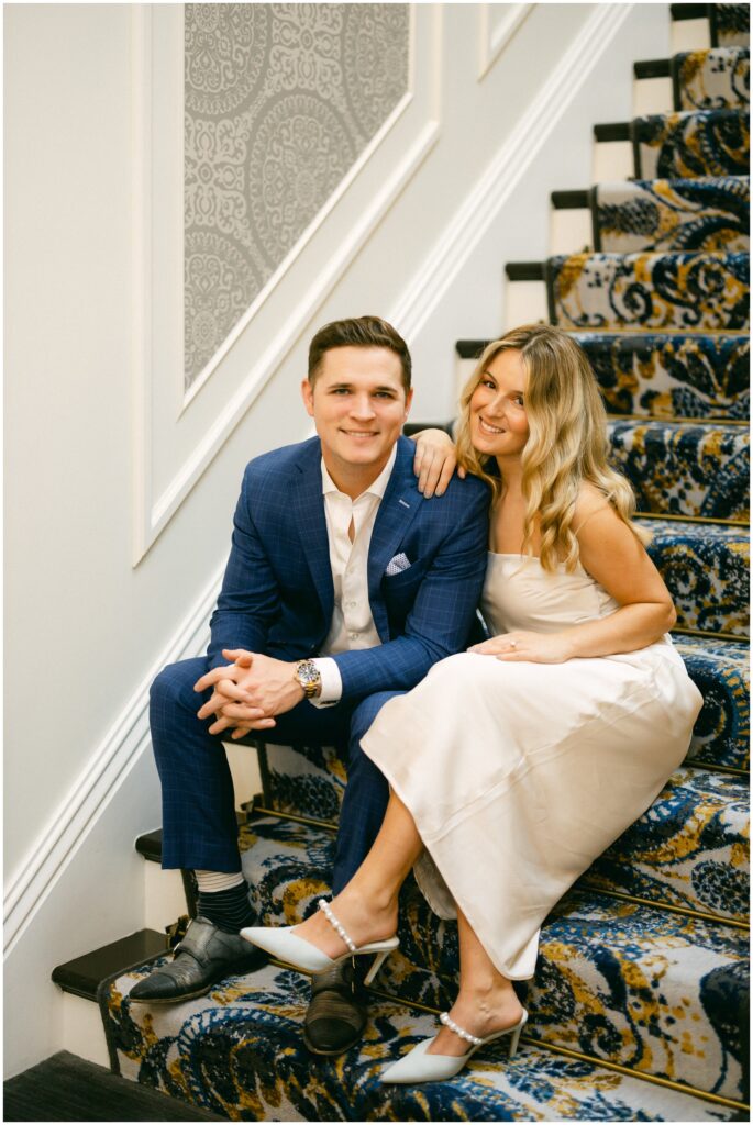 Newlyweds smile while sitting on some carpet stairs