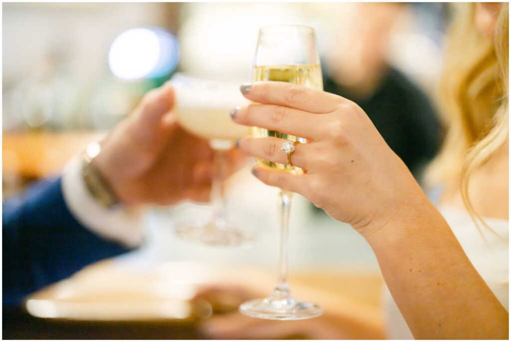 Details of a bride's ring on her hand while holding a glass of champagne