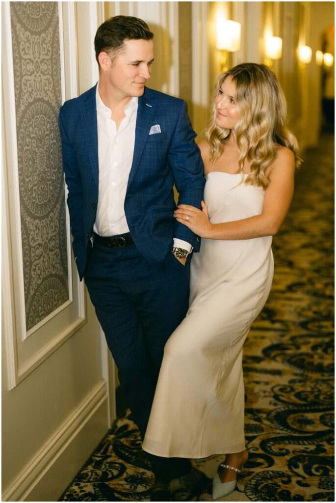 Newlyweds lean on a wall in a hallway at the adelphi hotel wedding while looking at each other