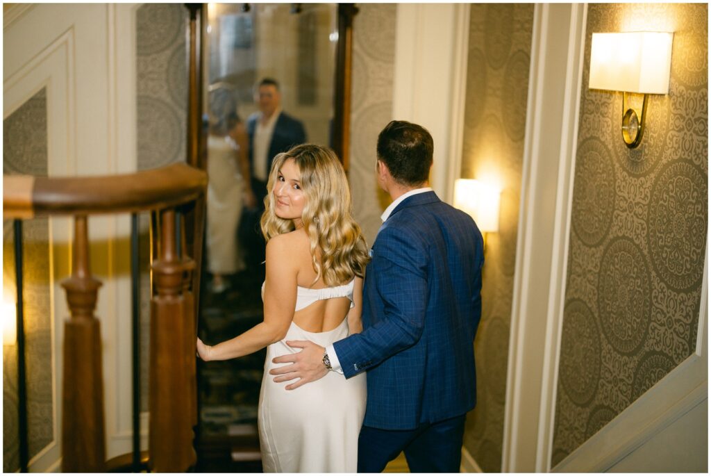 A bride looks over her shoulder while walking down the the adelphi hotel wedding venue stairs with her groom