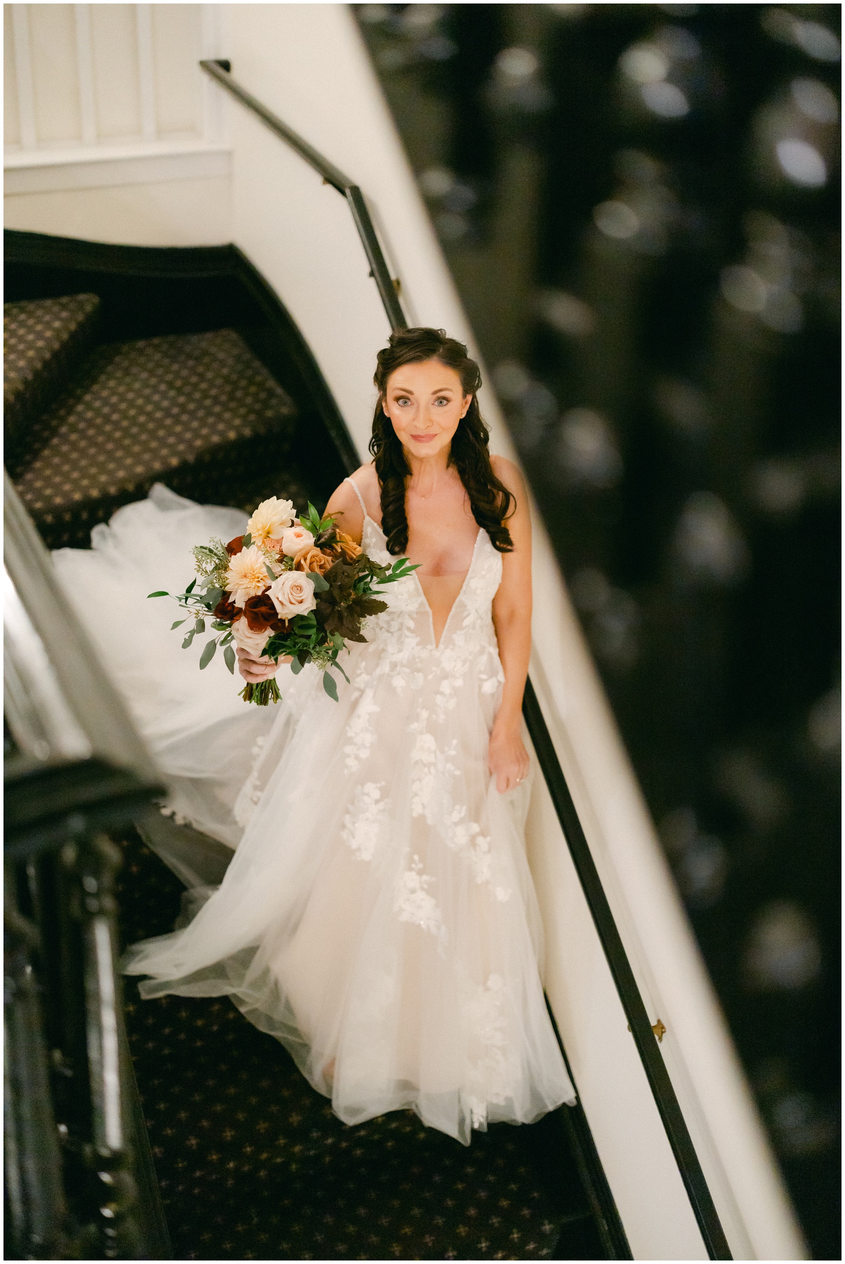 A bride walks down the long stairs in her lace dress