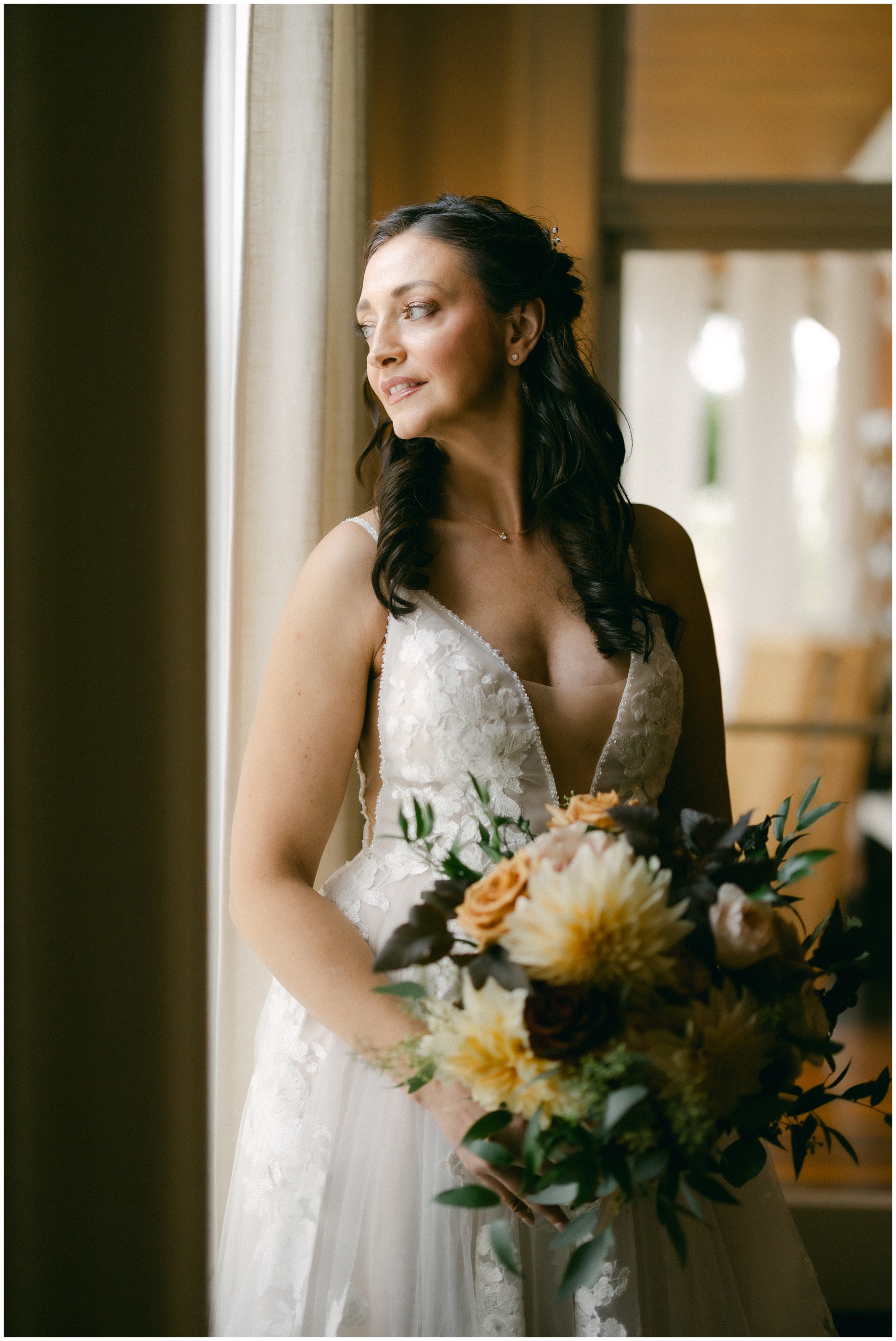 A bride gazes out a window in her dress at the mansion of saratoga