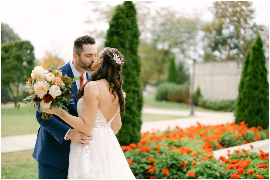 Newlyweds kiss in the gardens of red flowers