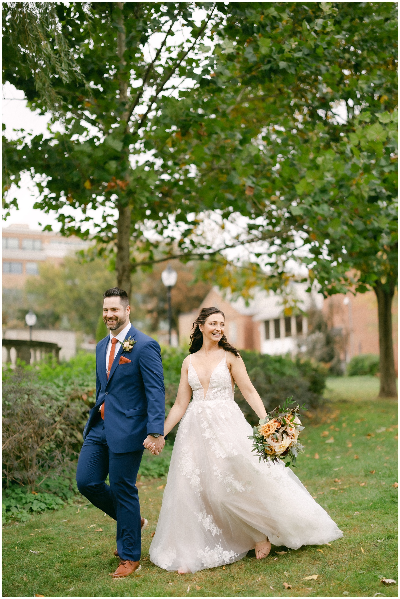 Newlyweds smile big while holding hands and walking through the gardens