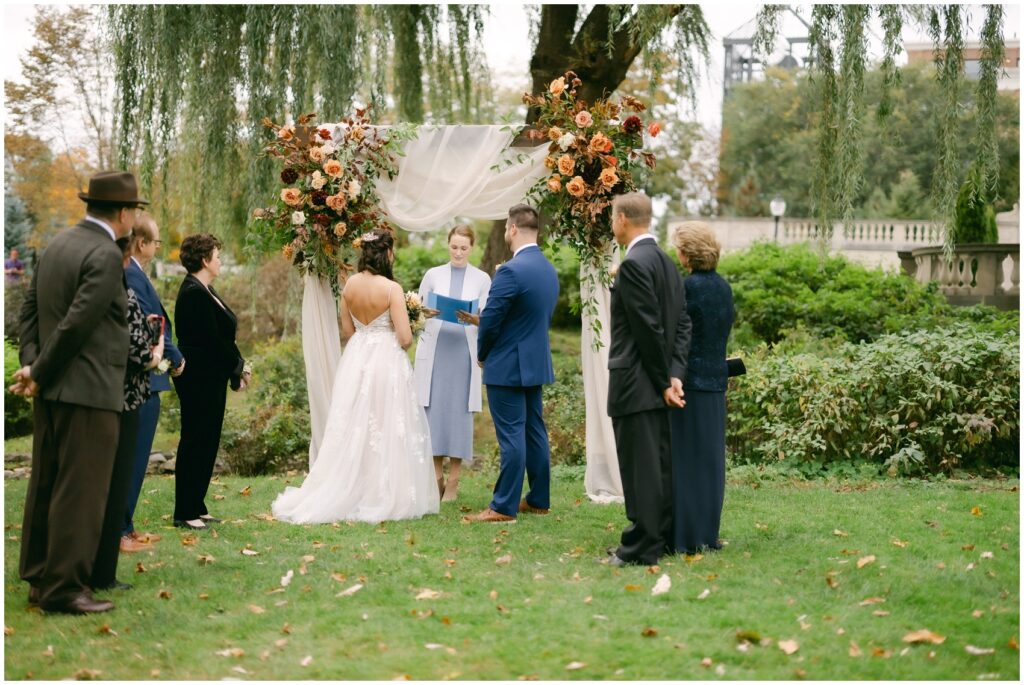 A bride and groom stand at the altar with their small number of guests and officiant