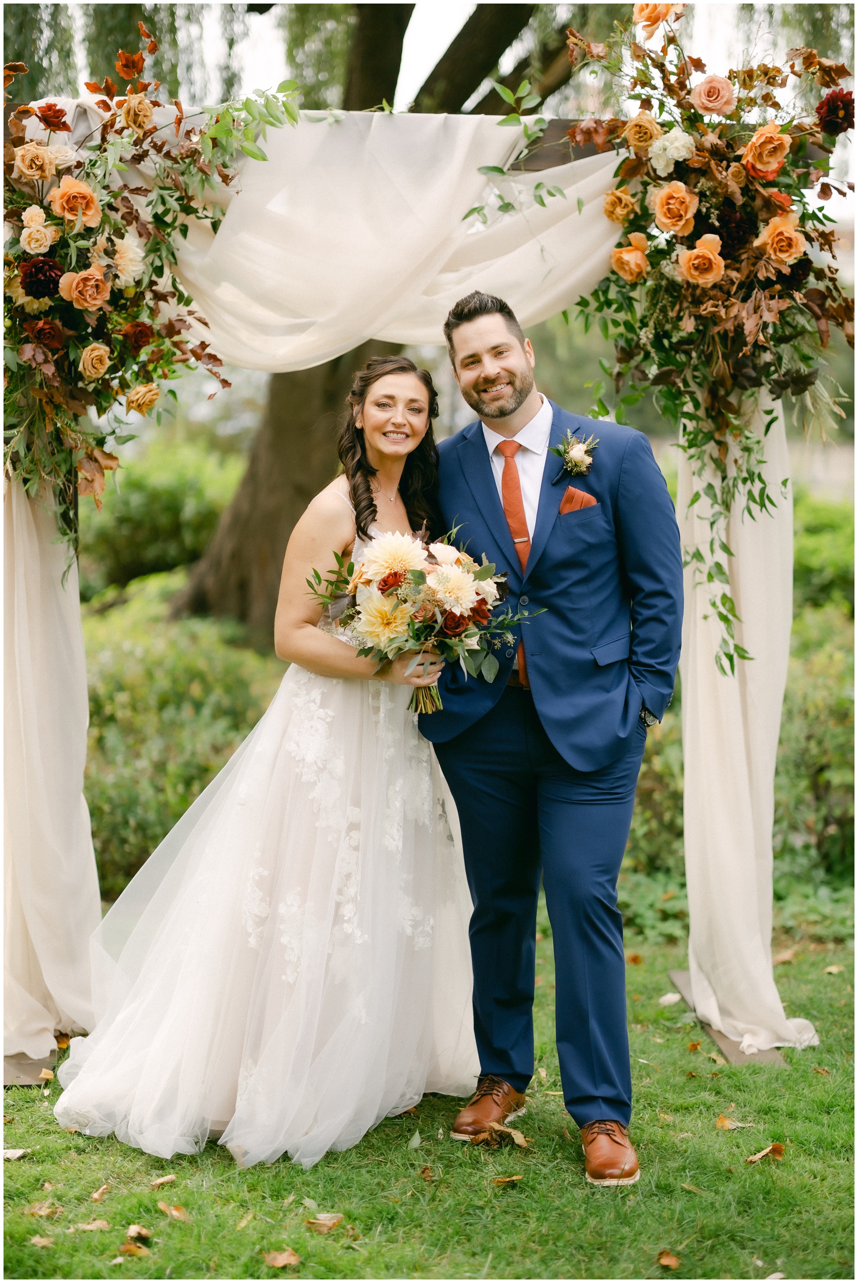 Newlyweds stand under the decorated arbor smiling together