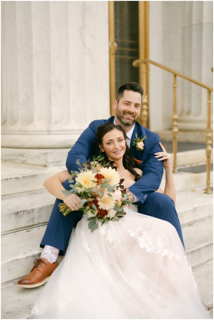 Newlyweds cuddle on marble steps during their the mansion of saratoga wedding